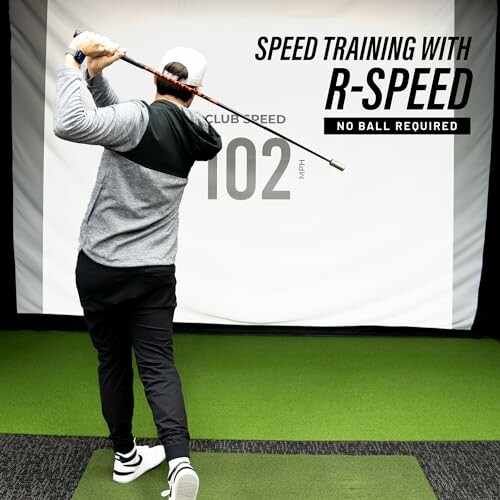 Golfer practicing swing with speed training equipment indoors.